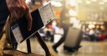 Pasoš, avionska karta i kofer u ruci na aerodromu